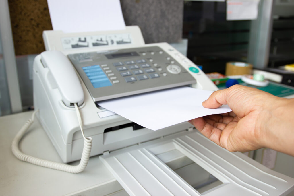 Hand man are using a fax machine in the office Business concept